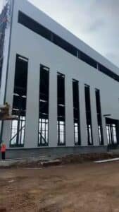 Trabajador ajustando los detalles de las ventanas en la fachada de naves industriales
