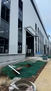 Esquina de nave industrial con grandes ventanales de vidrio y marquesina de entrada