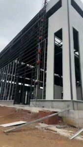 Detalle de columnas y vigas de acero oscuro soportando el revestimiento de naves industriales