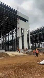 Trabajadores instalando paneles de fachada en naves industriales prefabricadas suministradas por fábrica china.