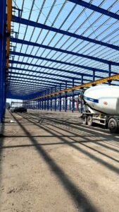 Perspectiva kilométrica del vertido de concreto en el piso de bodegas masivas con estructura de acero importada desde China.