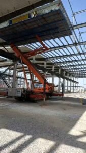 Trabajadores instalando el revestimiento exterior metálico en la estructura secundaria de un centro logístico