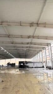 Instalación precisa de perfiles de acero y correas laterales para el cerramiento perimetral de un galpón metálico logístico.