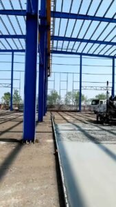 Detalle de maquinaria extendiendo concreto en la base de sólidas columnas de bodegas de acero prefabricadas