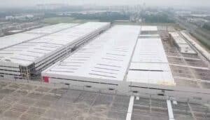 Fases simultáneas de construcción: galpones terminados junto a estructuras de acero en proceso de montaje.