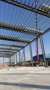 Heavy-duty industrial metal building installation using a crane for roof framework.