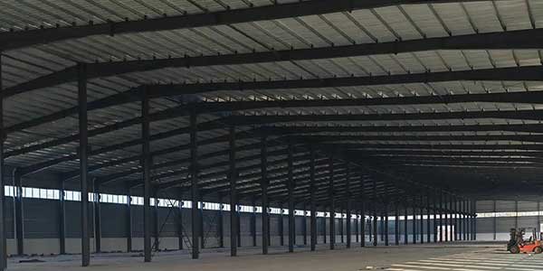 The internal structural steel frame of a giant metal building featuring rigid portal frames.