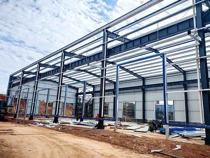 Trabajadores instalando paneles de acero en la fachada para montaje de galpones rápidos