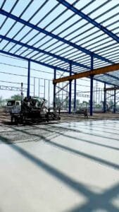 Máquina niveladora láser trabajando el concreto fresco en el interior de bodegas de almacenamiento de gran escala.