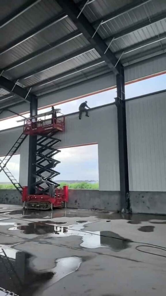 Grúa izando columnas de acero rojo pintadas con anticorrosivo para el mercado de estructuras metálicas importación exportación