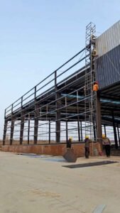 Grúa realizando el izaje de pórticos de acero de alta resistencia para galpones prefabricados chinos en un proyecto industrial.