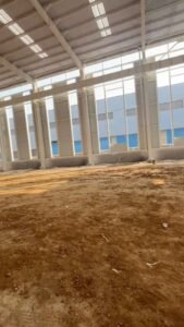 Grúa elevando componentes estructurales durante el montaje fluido de galpones importados de China.