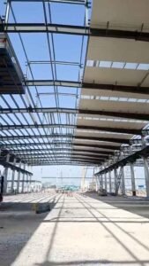 Grúas instalando las vigas del techo y correas galvanizadas en un proyecto de centro logístico de gran escala