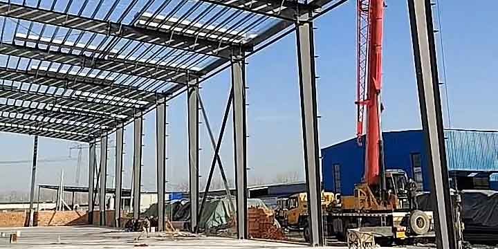 Construction workers safely installing roof panels on a large prefabricated metal building framework.