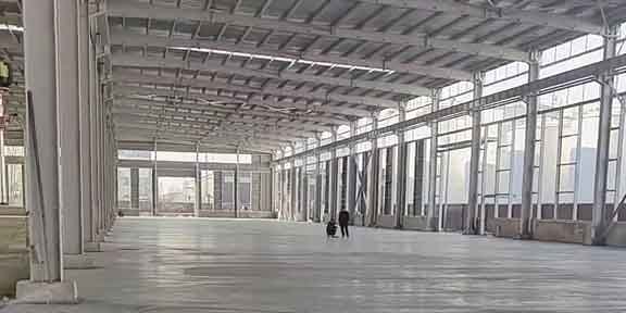 Taller de producción equipado con grúas puente manejando vigas H para proyectos de estructura metálica pesada.