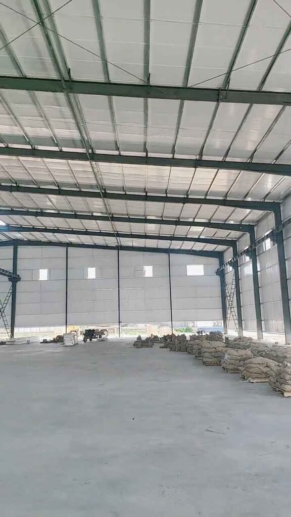 Interior espacioso de bodegas industriales con piso de concreto liso y múltiples sacos de material apilados en el lado derecho.