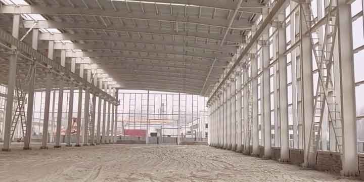 Construcción de estructuras metálicas mostrando una larga alineación de columnas laterales y arriostramientos verticales en forma de cruz.