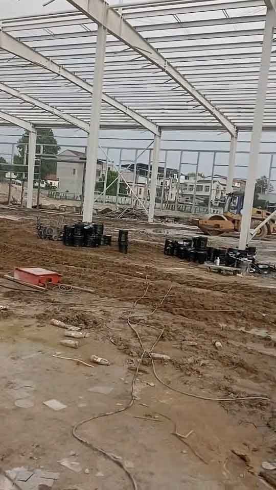 Columnas y vigas blancas de una estructura de acero para fábrica, destacando claramente los tensores de arriostramiento en forma de X en las paredes.