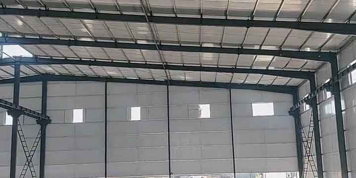 Detalle del techo de estructuras de acero con correas Z/C y paneles de pared blancos con pequeñas ventanas para iluminación.