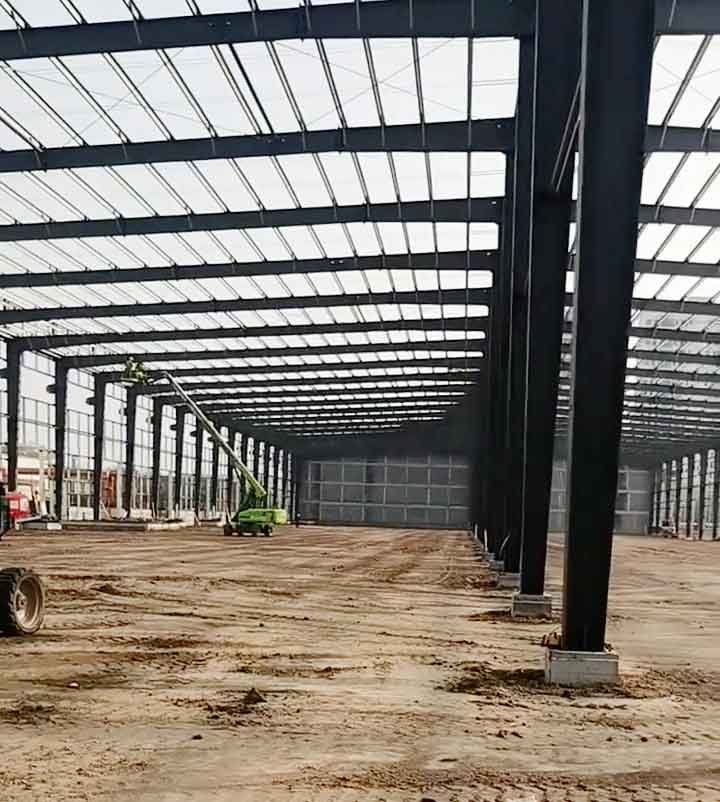 Estructuras metálicas principales y secundarias instaladas en una amplia nave con suelo de tierra, mostrando una plataforma de elevación al fondo.