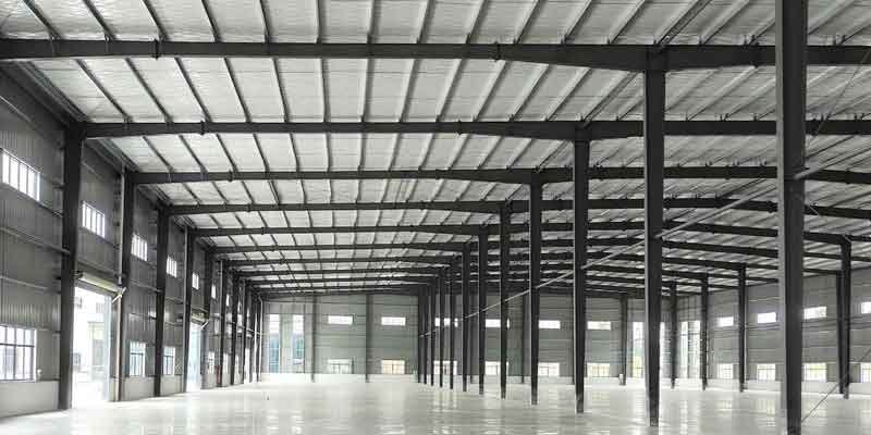 Interior de una fabrica de galpones metalicos con vigas tipo H, aislamiento térmico de aluminio y láminas traslúcidas para ahorro energético en Colombia