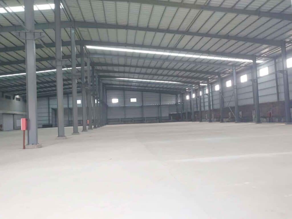 Amplia planta industrial de una fabrica de galpones metalicos con pisos nivelados y estructura de acero de luz libre sin columnas intermedias.