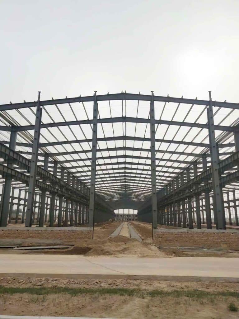 Detalle de la fijación y traslape de paneles de techo azules que garantizan impermeabilidad en un depósito logístico de distribución.