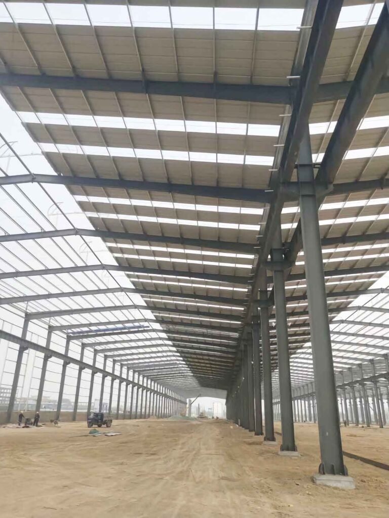 Operario en plataforma elevadora instalando paneles de muro con aislamiento para un depósito logístico eficiente