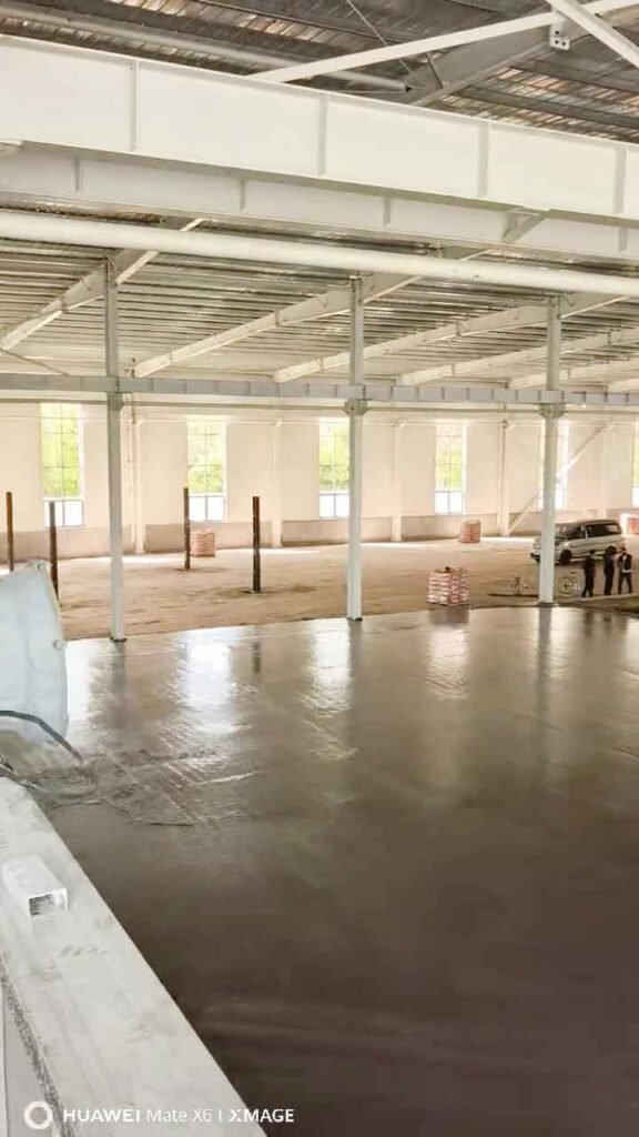 Reflejo luminoso de la luz natural de las ventanas sobre el piso de concreto recién pulido dentro de espaciosos almacenes metálicos.