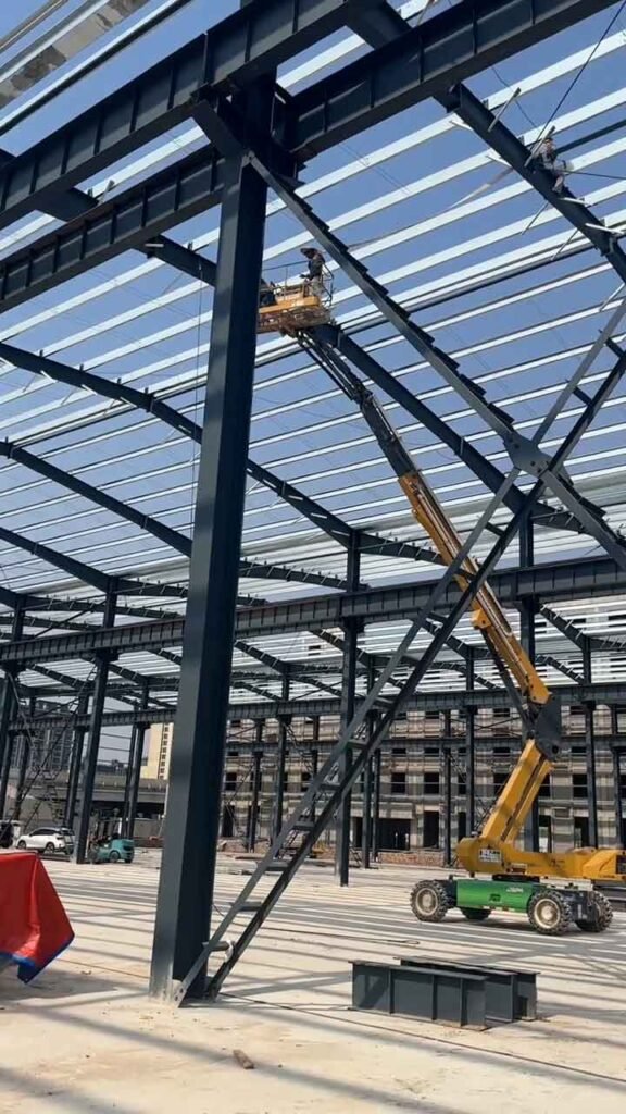 Grúa telescópica y plataforma elevadora trabajando en la techumbre de un almacén industrial moderno.
