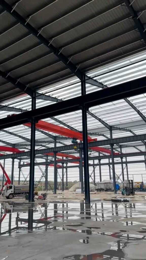 Interior de una bodega industrial prefabricada equipada con múltiples puentes grúa para carga pesada.