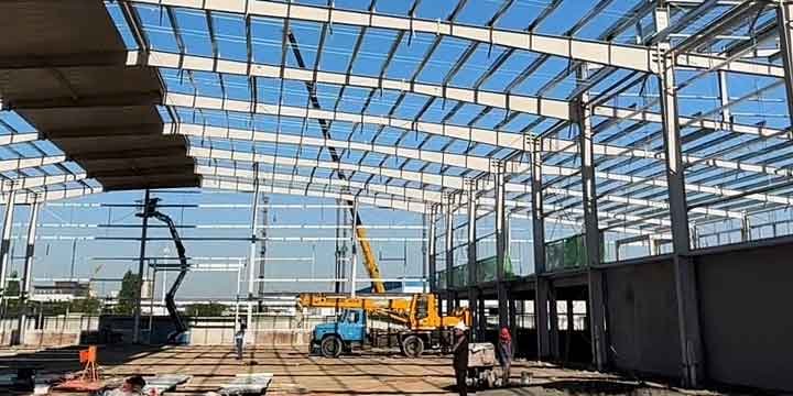 Vista general de un complejo de bodegas industriales modernas en proceso de levantamiento con grúas telescópicas.