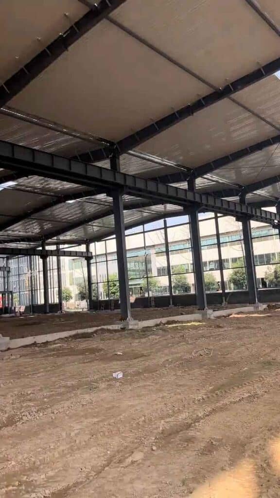 Fase de construcción de bodegas metálicas mostrando los pilares de acero anclados a fundaciones de hormigón.