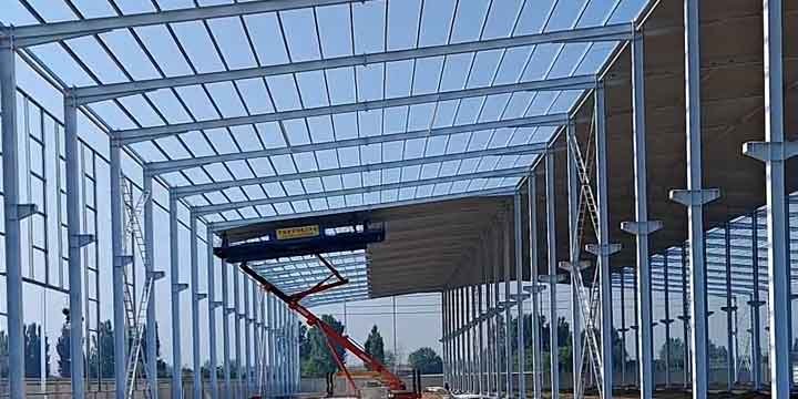 Uso de plataforma elevadora roja para una construcción industrial eficiente durante la fijación de la cubierta metálica superior.