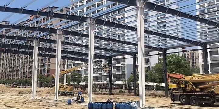 Vista panorámica de la construcción industrial rápida de un edificio de acero con camión grúa y personal de montaje.