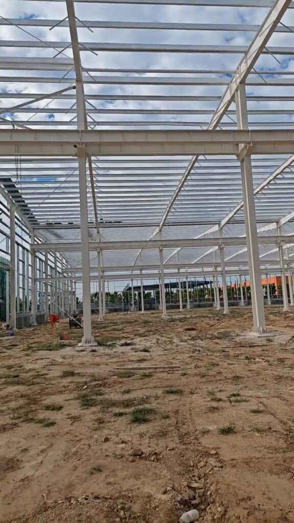 Panorama interior de una nave industrial en construcción sobre suelo nivelado, ejemplo de calidad de una empresa de estructuras industriales prefabricadas.