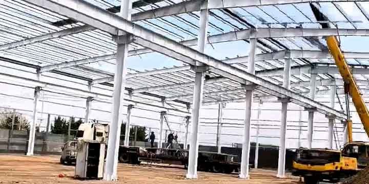 Uso de grúa telescópica amarilla en el levantamiento de una estructura metálica industrial de gran envergadura a cielo abierto.