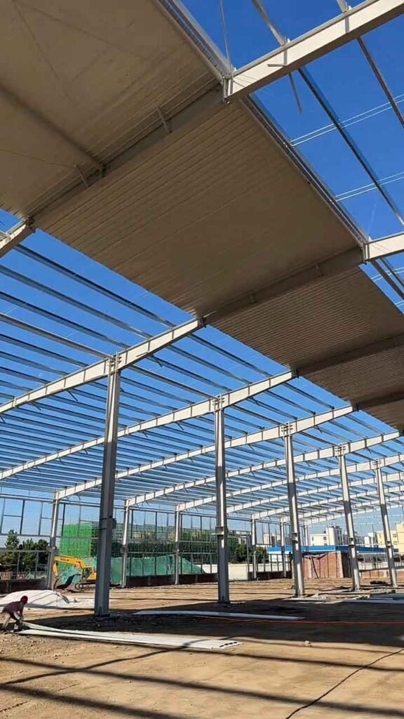 Vista interna de la estructura metálica industrial con correas tipo C y vigas maestras bajo un cielo despejado.