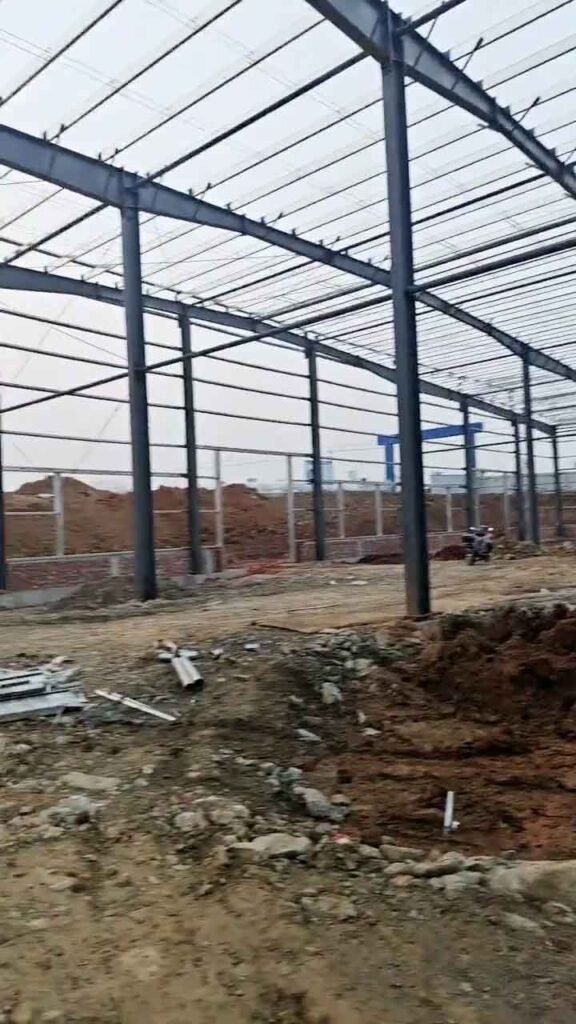 Montaje inicial de un galpón industrial prefabricado con columnas de acero reforzado en terreno preparado