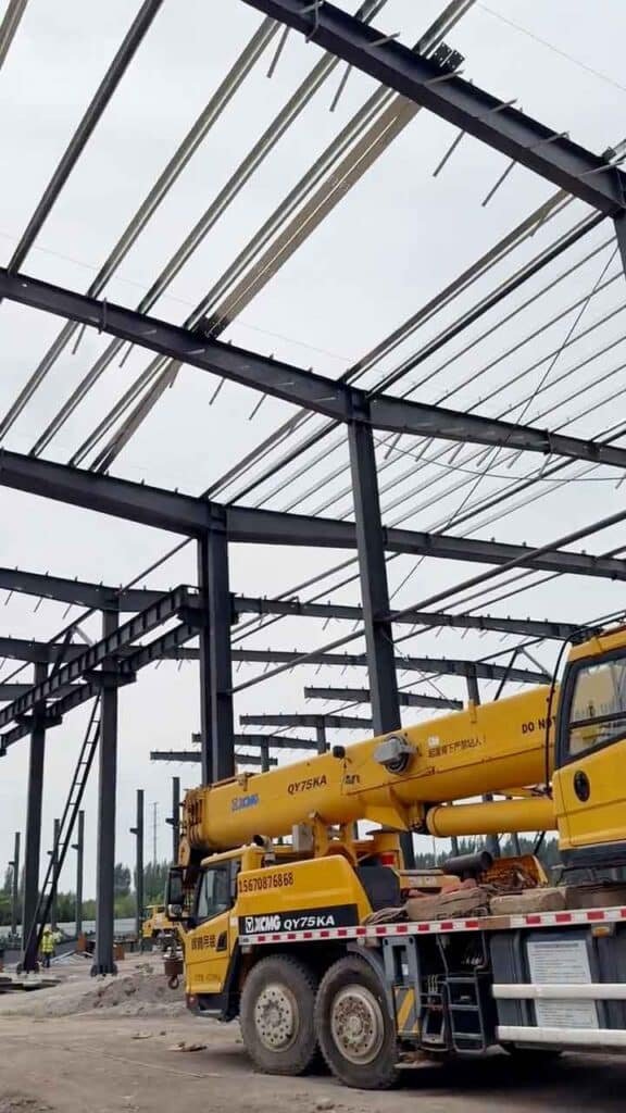 Montaje de galpón prefabricado de acero utilizando grúa pesada en sitio de construcción.