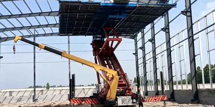 Grúa y plataforma elevadora ajustando los paneles de la techumbre de un galpón prefabricado de acero.