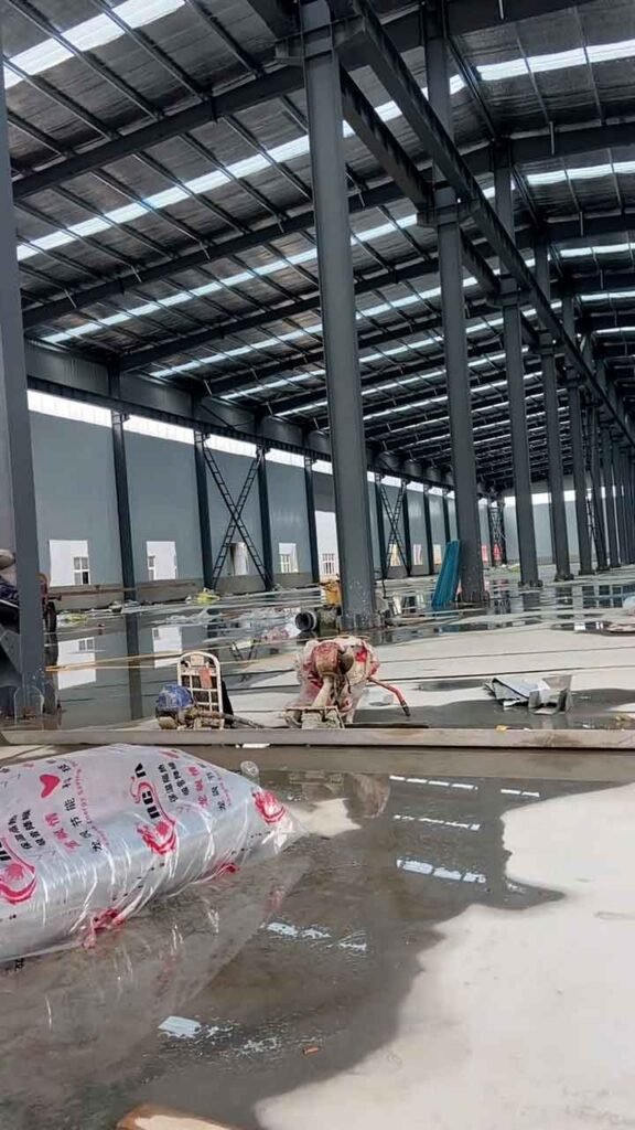 Pavimentación interior y esqueleto metálico de un modular warehouse building en etapa de acabados de radier.