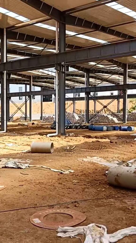 Columnas de acero de una nave industrial económica con bajantes pluviales de PVC blanco instalados.