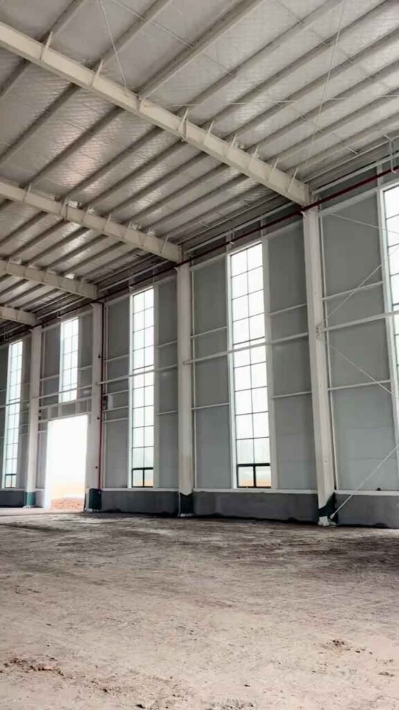 Interior de nave con ventanales verticales y techumbre aislada para consultar precio estructura metálica industrial