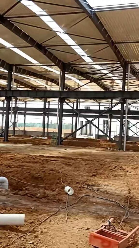 Terreno sin pavimentar y conexiones de vigas de acero usadas para calcular el precio galpón industrial por m2.