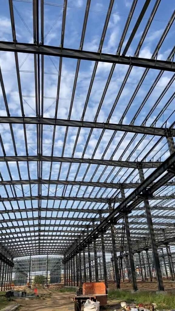 Complejo de edificios industriales prefabricados de acero en etapa de montaje estructural bajo cielo despejado.