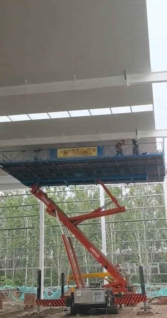 Uso de plataforma elevadora roja para el montaje final de un proveedor de estructuras metalicas prefabricadas en sitio de obra.