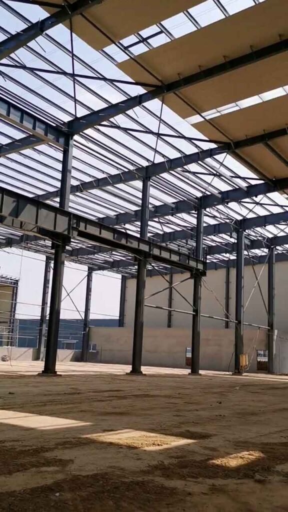 Profunda perspectiva de estructuras de acero para industria, destacando la fuerte viga horizontal carrilera iluminada por el sol, diseñada para soportar una grúa.