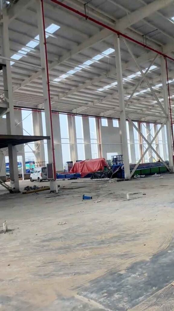 Espacio interior diseñado para soluciones logísticas, mostrando equipos y materiales protegidos con lonas rojas y azules en el centro de una nave con grandes aberturas perimetrales de luz.