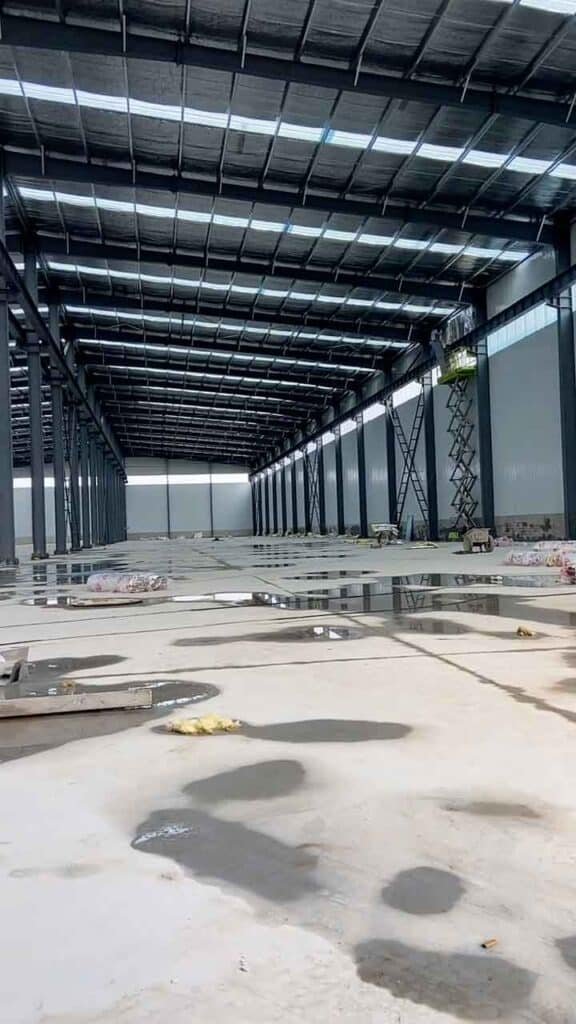 Estructura interna de un steel warehouse building con techo de panel sándwich y sistema de iluminación cenital.